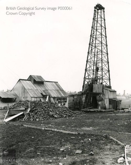 The mighty drilling derrick, and corrugated iron shed containing steam engine and boilers.
